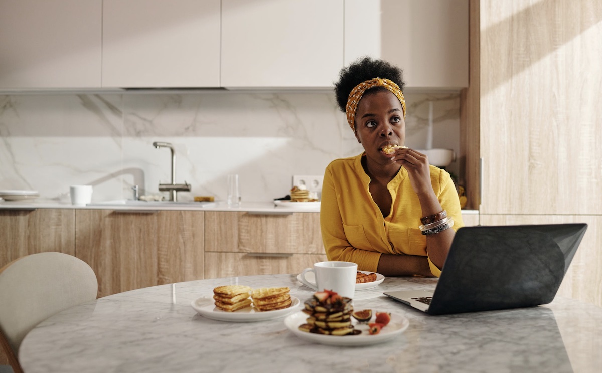 Woman eating alone in kitchen Image: Pexels - Diva Plavalaguna
