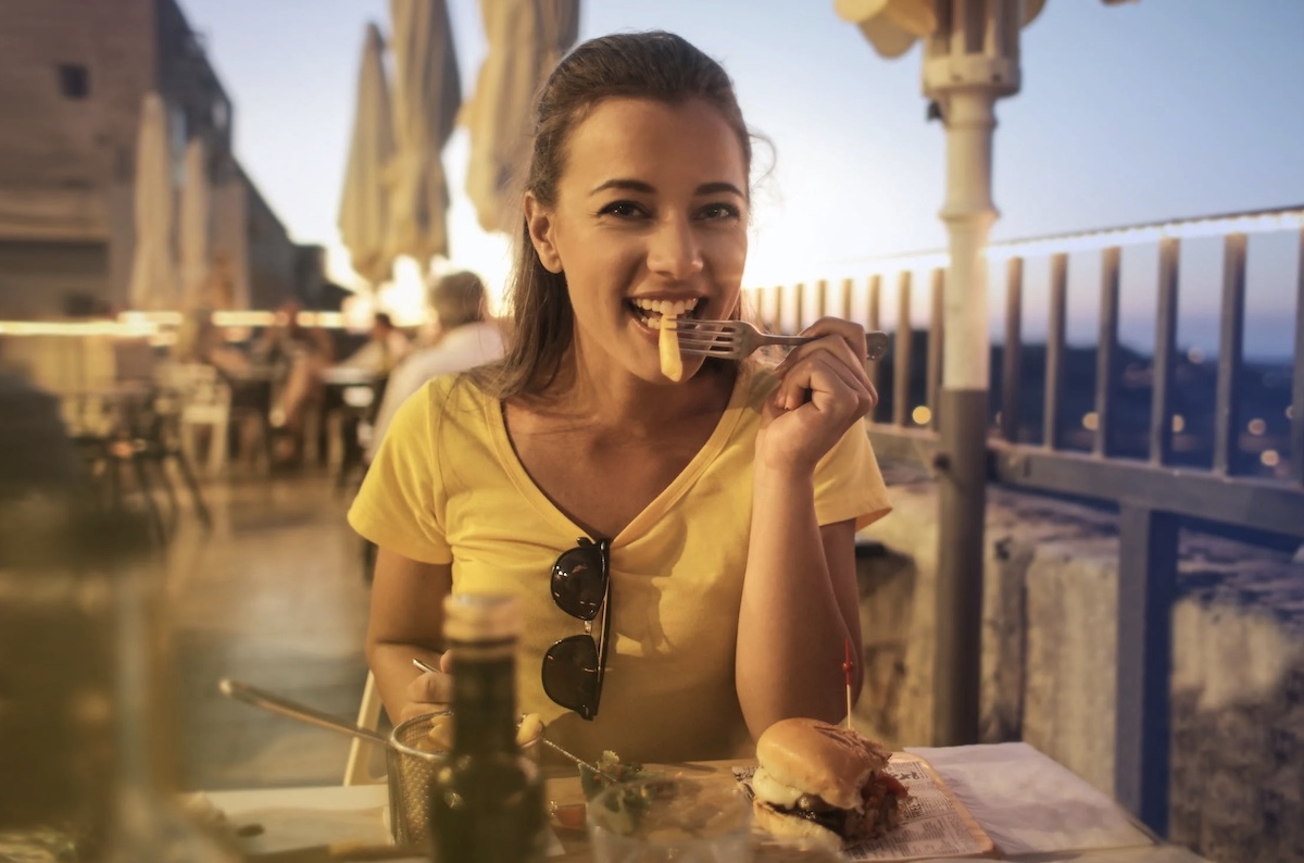 Woman eating fries outside. Image: Pexels - Andrea Piacquadio