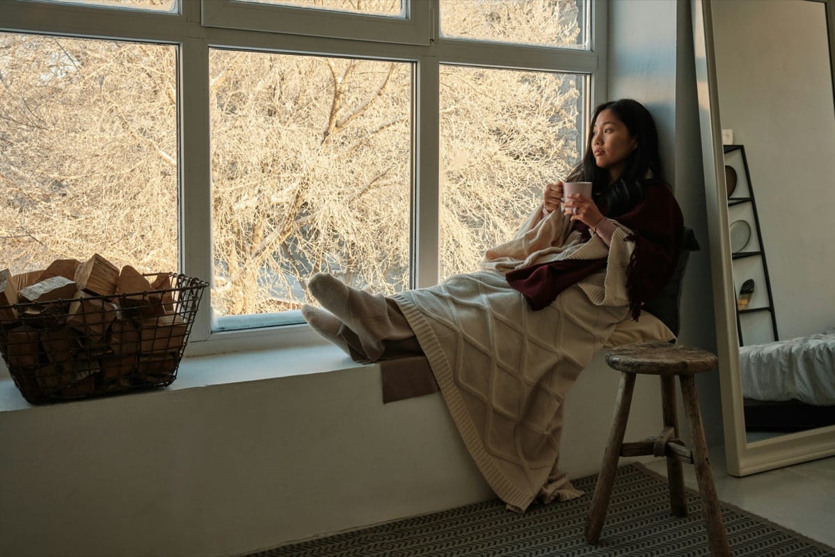Women relaxing in the window with a hot tea, reflecting on life.
