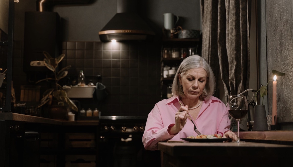Woman eating dinner with a glass of wine. Image: Pexels - cottonbro studio