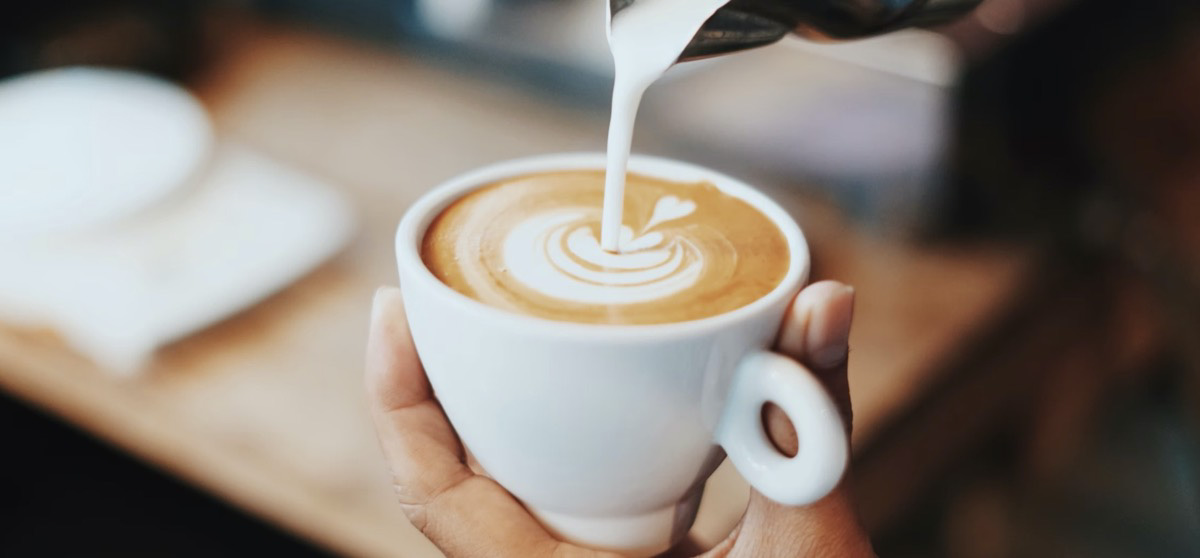 Pouring milk into a coffee. Unsplash - Fahmi Fakhrudin