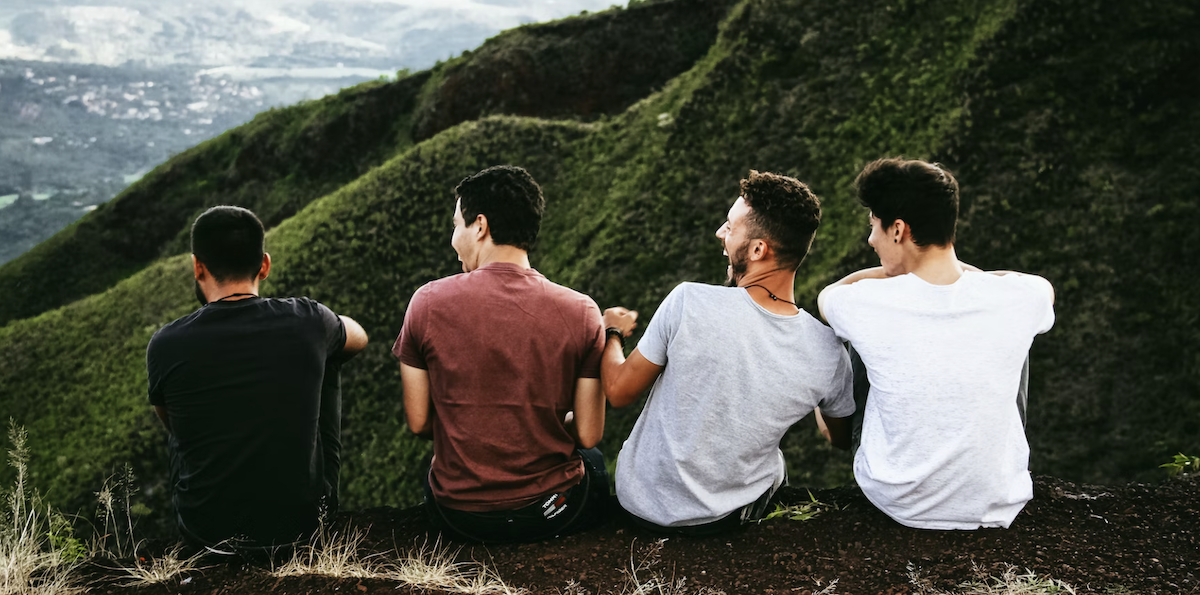 Men sitting together on top of mountain. Image: Unsplash - Matheus Ferrero