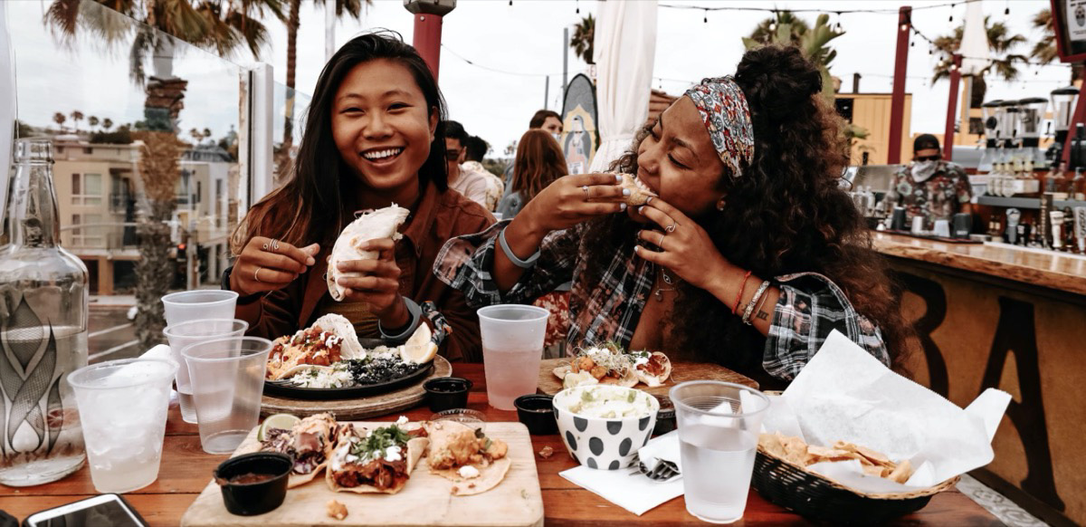 Two girls enjoying a meal out while traveling Unsplash - kevin turcios