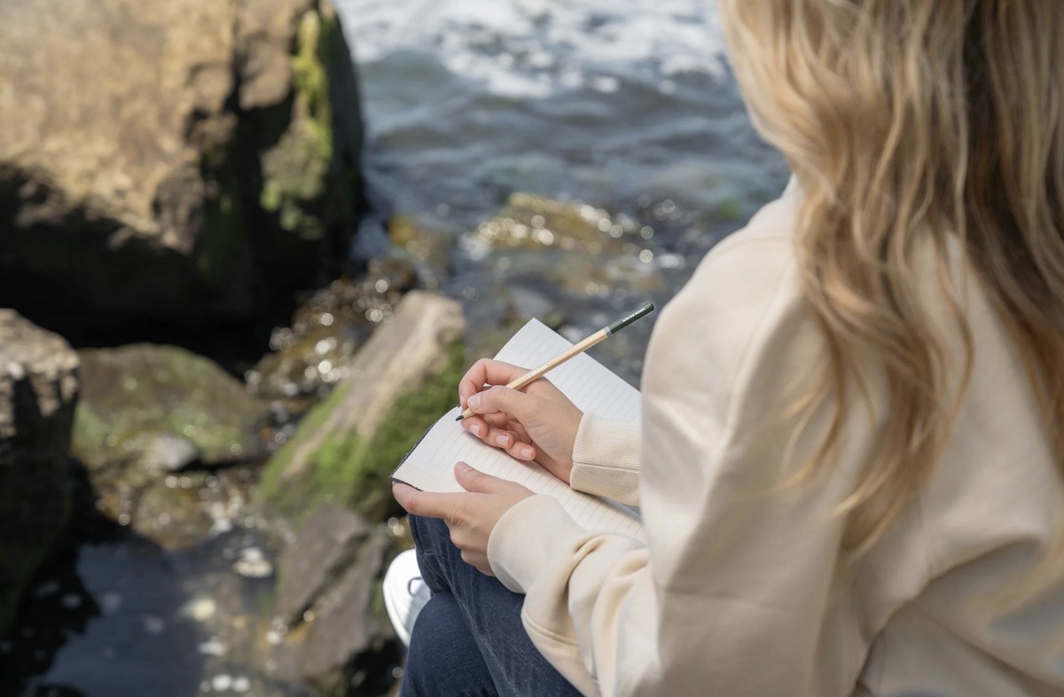 Woman sitting on rocks and journaling. Image: Pexels - Kevin Malik