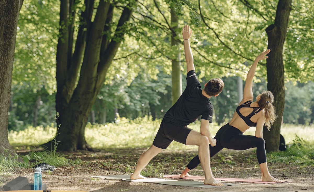 Man and woman doing yoga in park. Image: Pexels - Gustavo Fring
